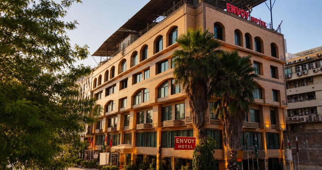 a building with a palm tree in front of it at Envoy Continental Hotel, Blue Area, Islamabad in Islamabad