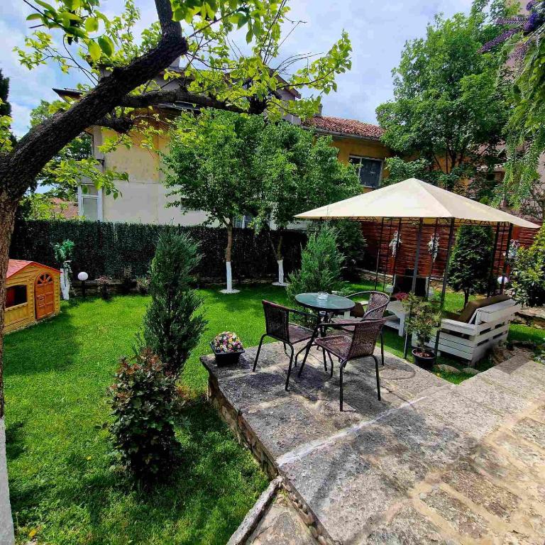 a patio with a table and chairs and an umbrella at Guest House Simon Green in Balchik