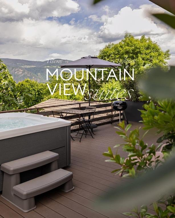 a deck with a hot tub and a table with an umbrella at Mountain View Suites in Tesimo