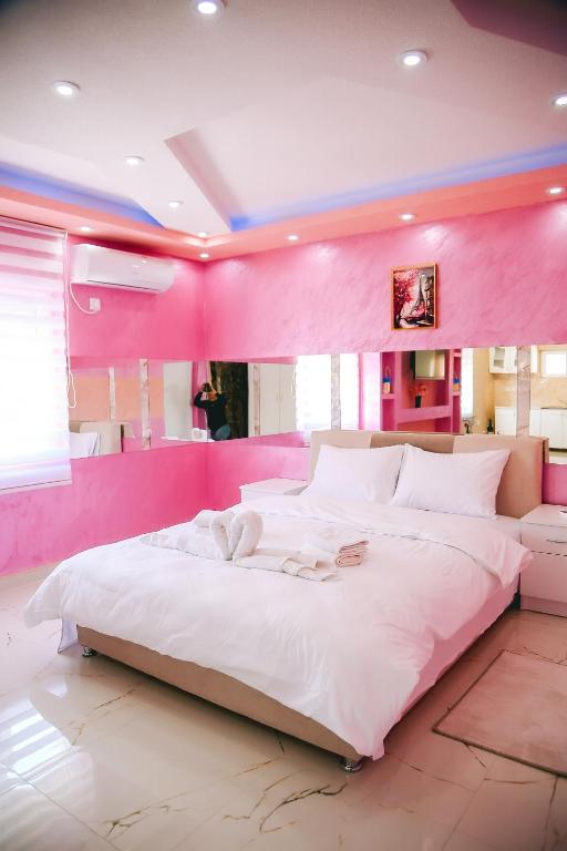 a pink bedroom with a large white bed in it at LUX apartman savić in Aleksinac