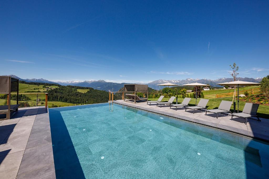 a swimming pool with chairs and umbrellas at Hotel Avelina in Avelengo