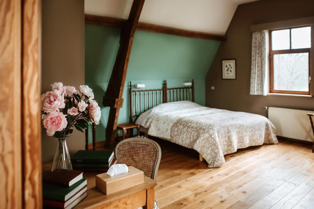 a bedroom with a bed and a vase of flowers at Haras de Baudemont in Ittre