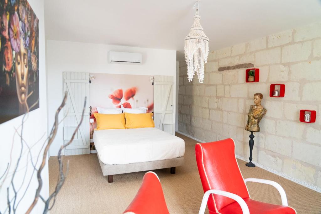 a bedroom with a bed and two red chairs at Parnaydisiaque in Parnay