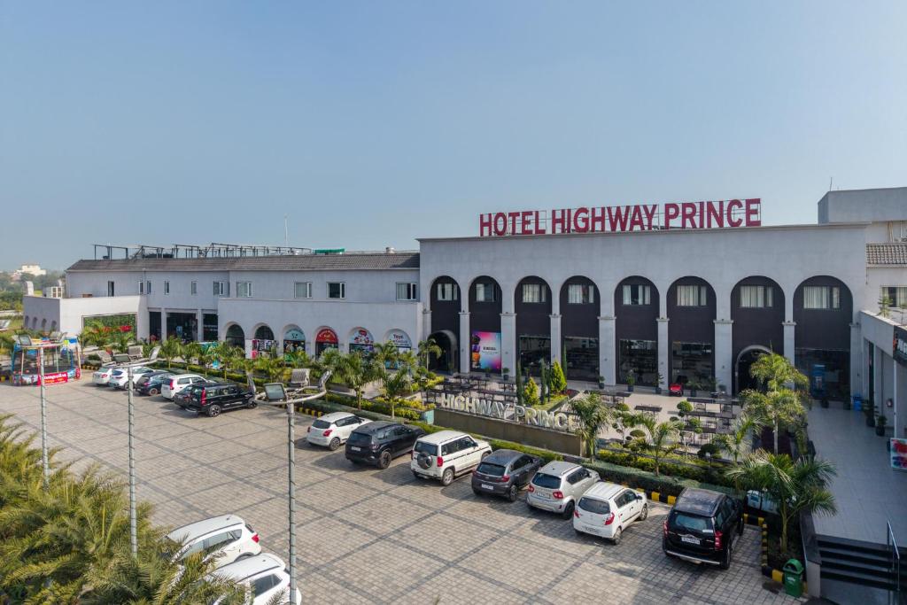 a parking lot with cars parked in front of a building at Hotel Highway Prince Behror in Behror
