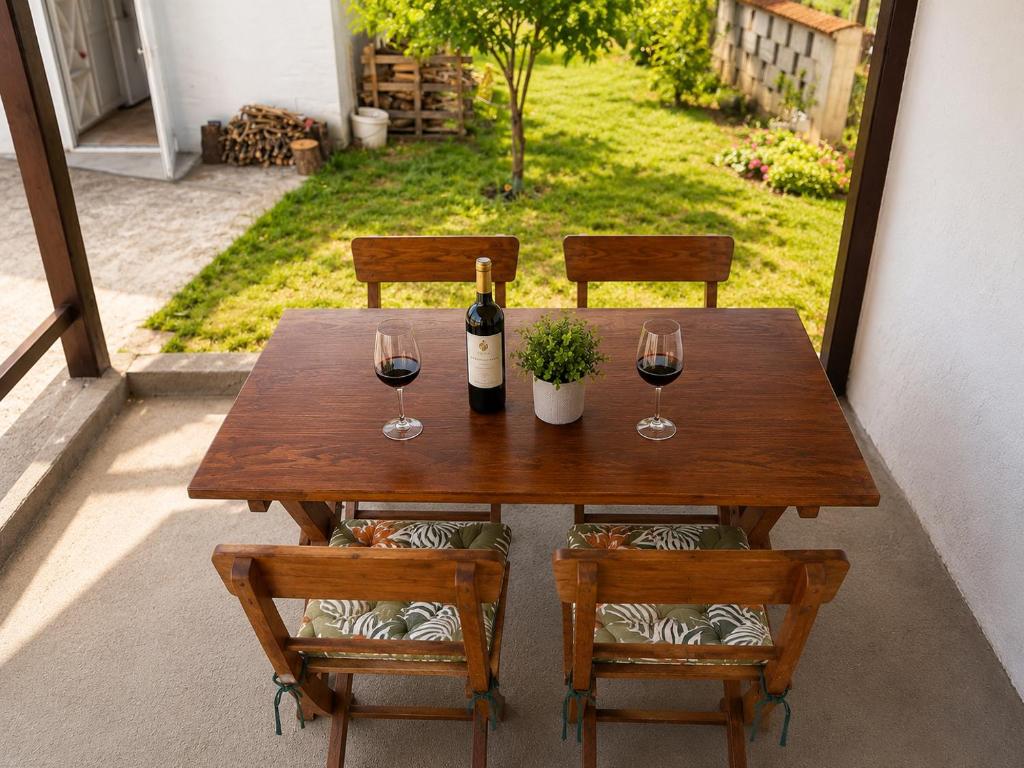 a wooden table with two glasses of wine and two chairs at Apartment Near Zadar Airport & City in Crno
