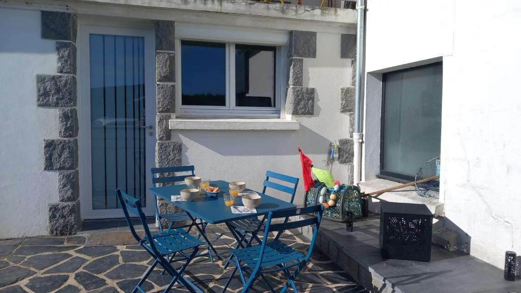 a blue table and chairs in front of a building at Studio cosy proche bourg et plages tout équipé in Plouhinec