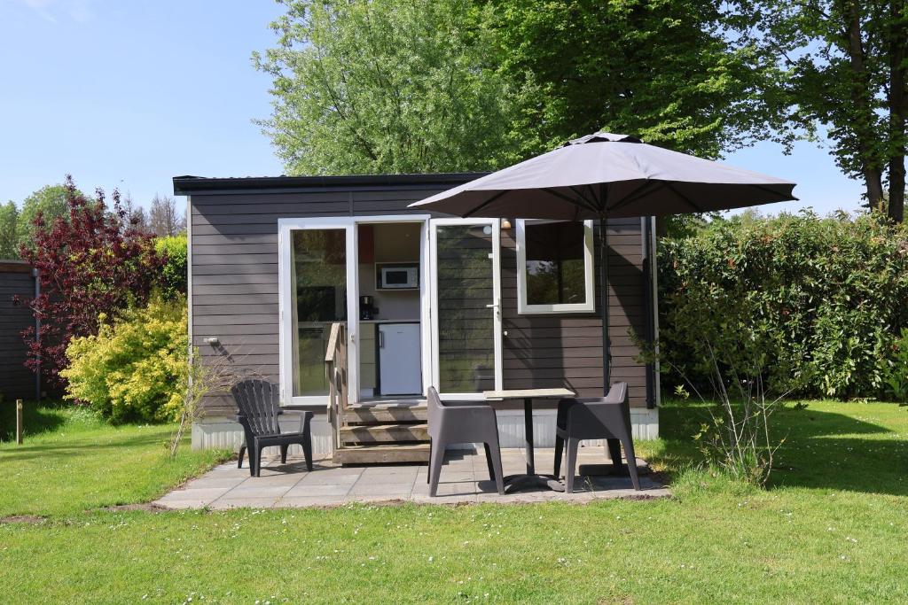 a small cabin with a table and chairs and an umbrella at Mini-chalet - Vakantiepark 't Urkerbos in Urk