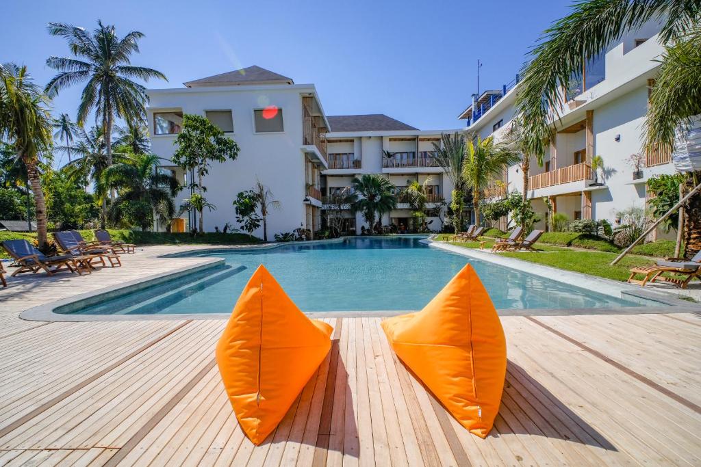 a swimming pool with orange umbrellas in front of a building at Giri Rose Boutique Hotel in Kuta Lombok