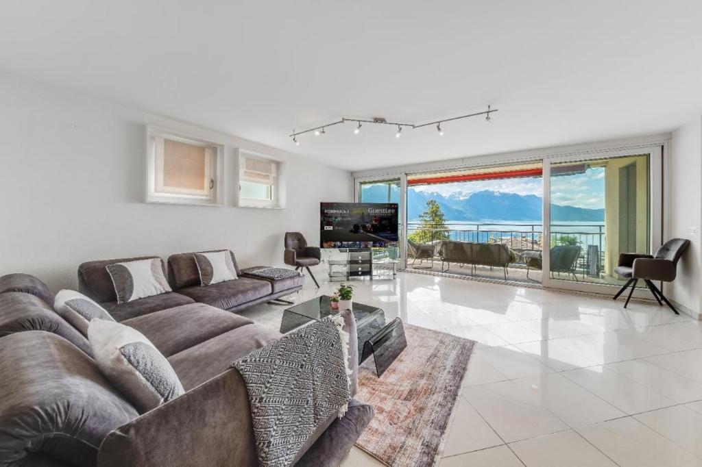 a living room with a large couch and a television at Spacious 3BR Lakeview Apartment with Terrace by GuestLee in Montreux