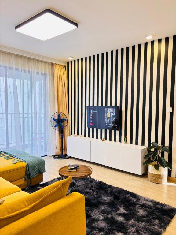 a living room with a yellow couch and a tv at Two-Bedroom Apartment Near JKIA & SGR Free Parking & Wi-Fi By Irene in Nairobi