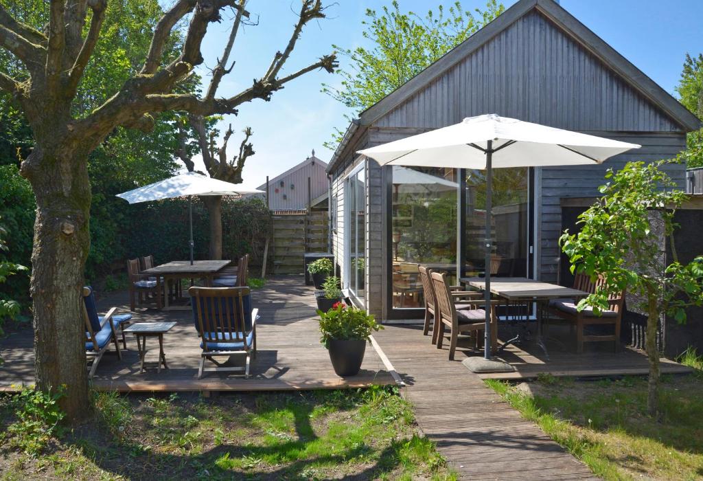 a patio with tables and chairs and umbrellas at Vakantiewoning MV8 in Egmond-Binnen