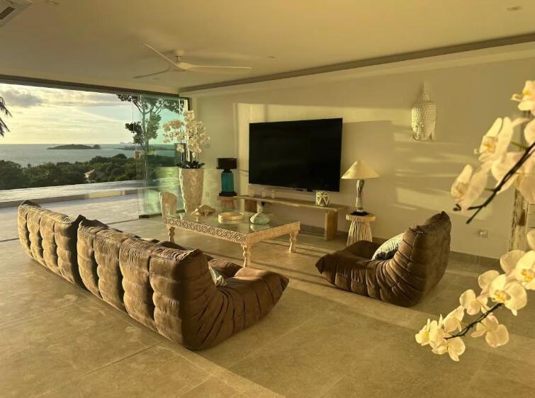 a living room with couches and a flat screen tv at Villa Bardi - Breathtaking Sea View in Plai Laem
