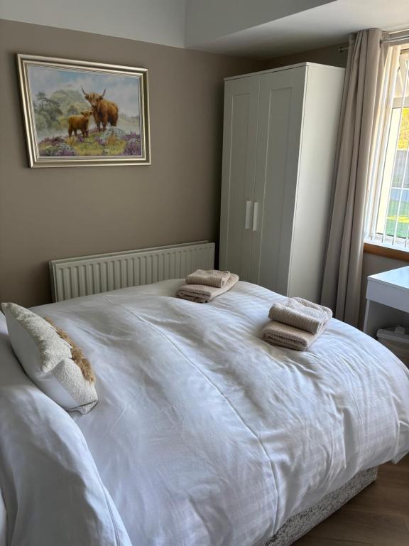a bedroom with a large white bed with pillows on it at 4 Glenfalloch Road in Crianlarich
