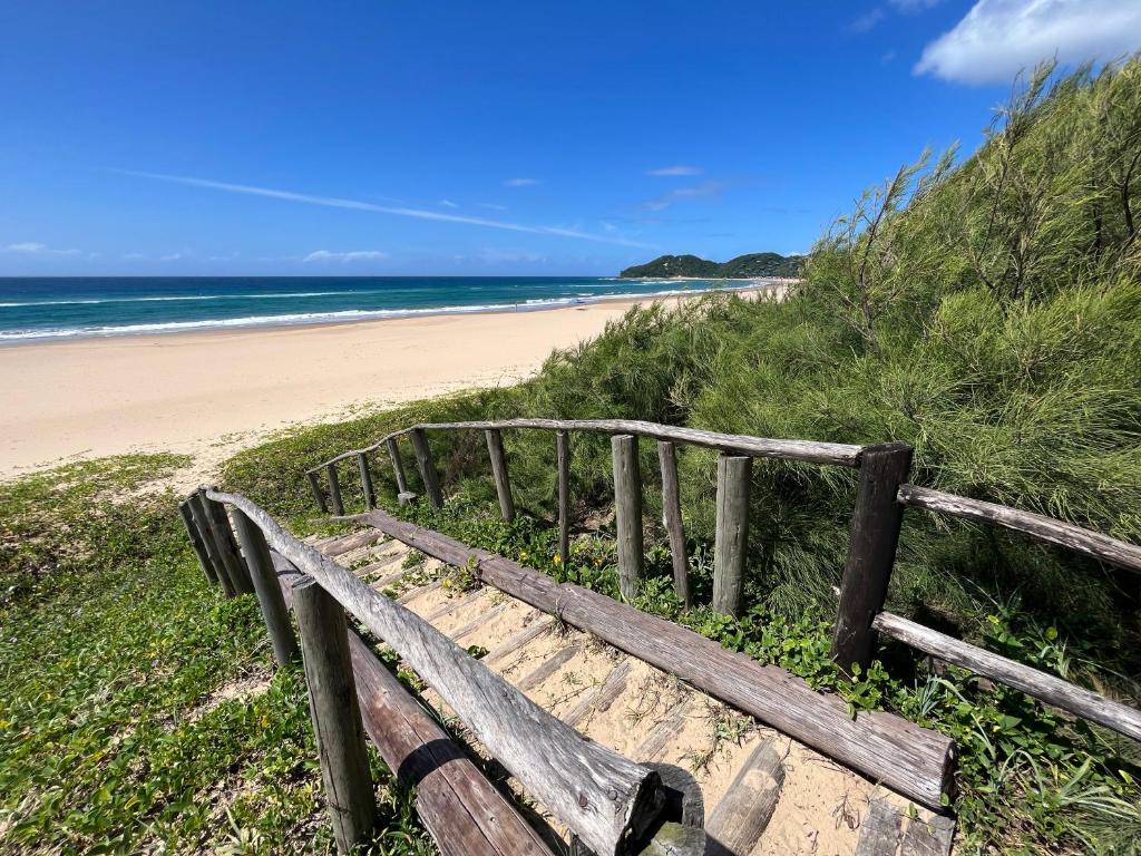 a wooden bench sitting on the side of a beach at Surfers Spot in Ponta do Ouro