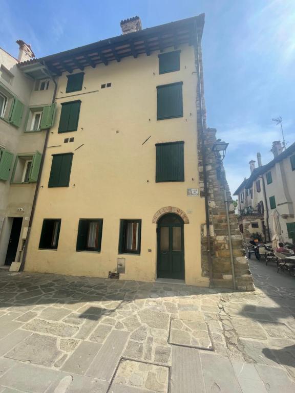 a large yellow building with green windows on a street at Calle del Palazzo 12 in Grado