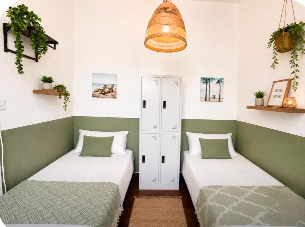 two beds in a room with green and white walls at Ria Surf & Stay in Faro