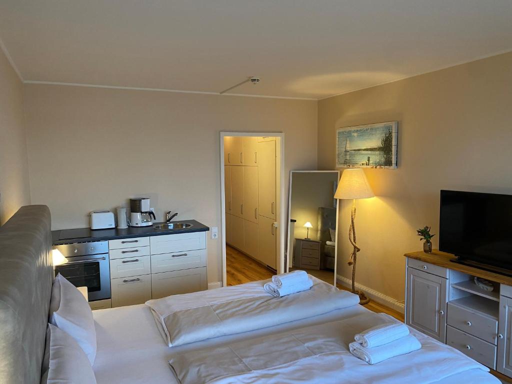 a room with two beds and a kitchen with a television at Fördeblick Anna in Glücksburg