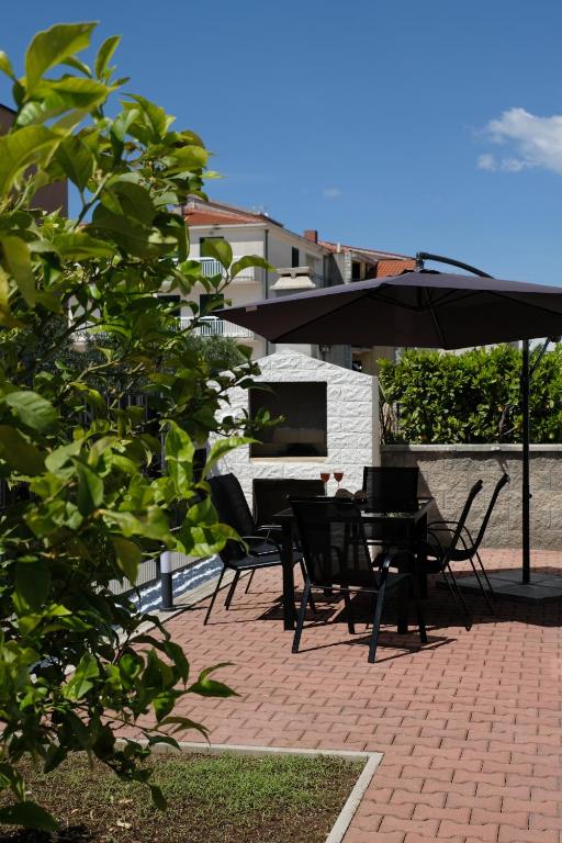 a patio with a table and chairs and an umbrella at Bokun Gušta in Trogir