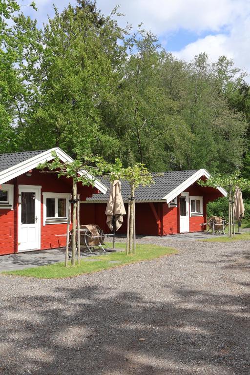 a red and white cabin with a porch and a patio at Vakantiepark 't Urkerbos - 5 persoons Brabantse blokhut in Urk
