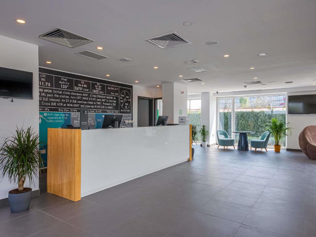 an office lobby with a white counter and chairs at Ibis Styles Bucharest Airport in Otopeni
