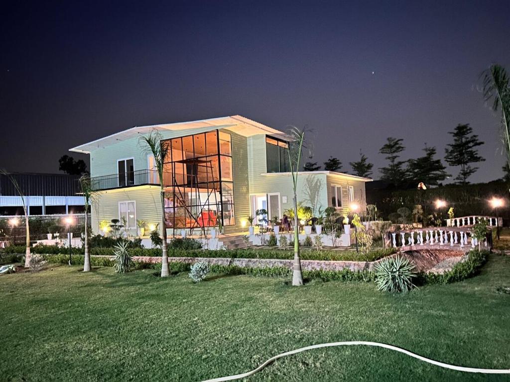 a house at night with a garden in front of it at Singhal's Farm House in Greater Noida