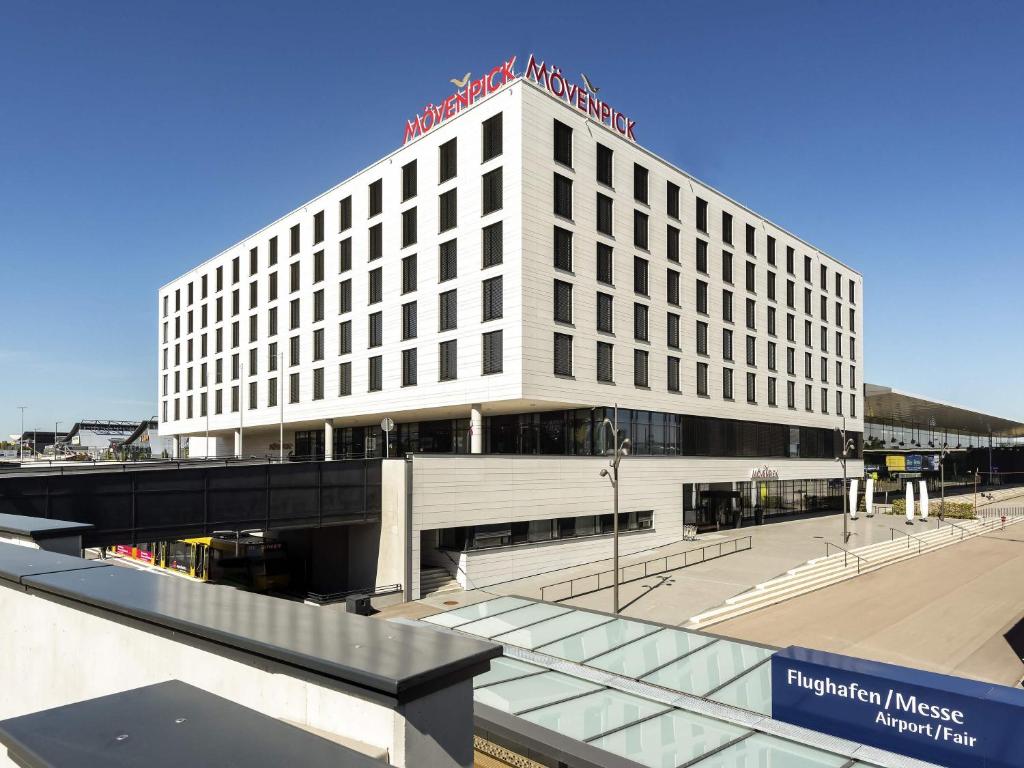 a large white building with a sign on top of it at MÖVENPICK Hotel Stuttgart Messe & Congress in Stuttgart