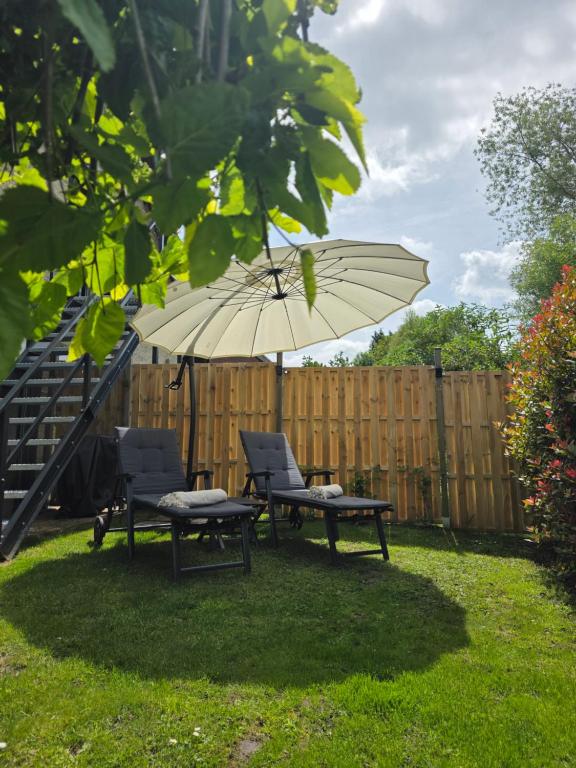 a patio with two chairs and an umbrella in a yard at StayTommy in Bertem
