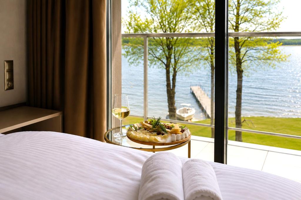 a bed with a plate of food and a glass of wine at Blue & Green Masurian Hotel in Węgorzewo