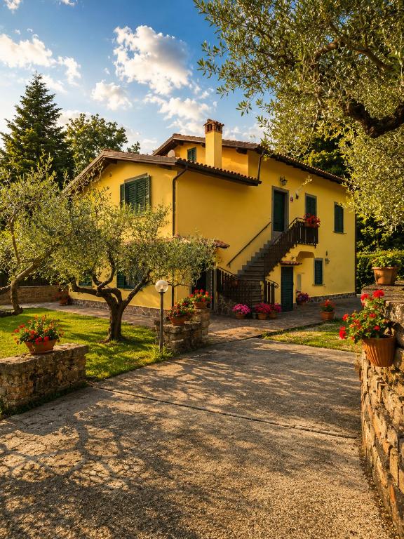 a large yellow house with trees and a driveway at Holiday House Nemi in Monte Porzio