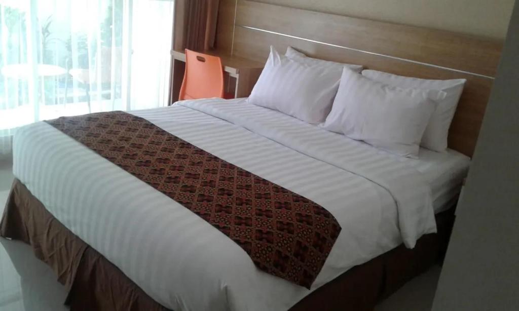 a bed in a hotel room with a white blanket and pillows at Hotel Ella Tambolaka in Tambolaka Airport