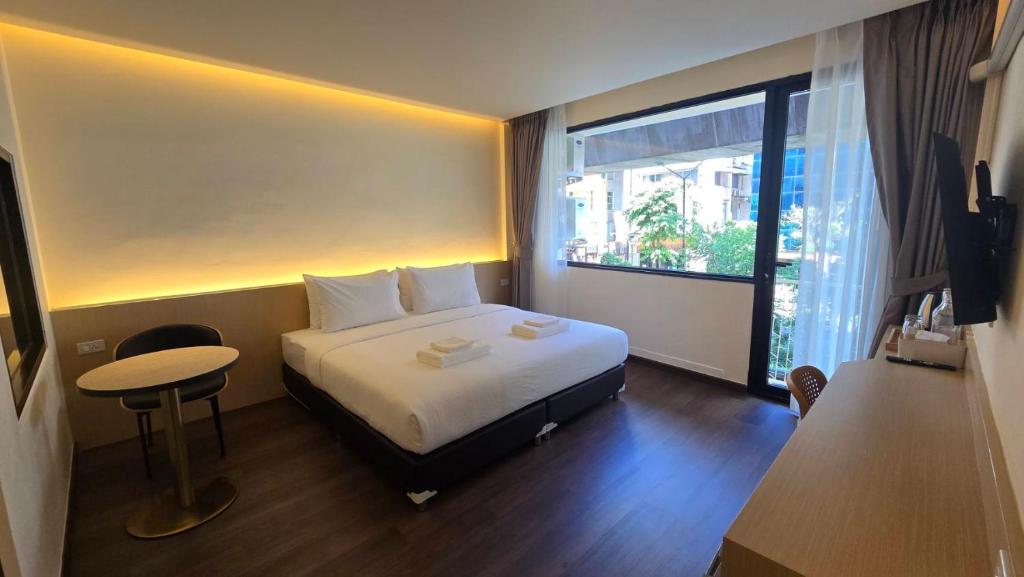 a hotel room with a bed and a table and a window at Norns Silom Cafe & Stay in Bangkok