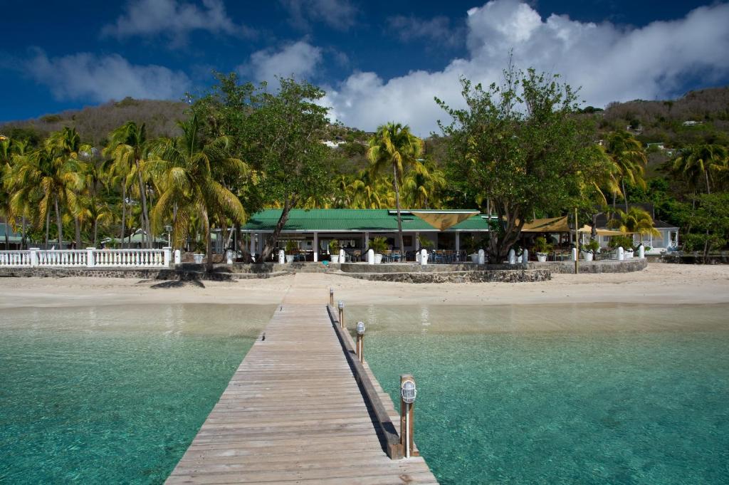 a wooden dock in the water next to a beach at Bequia Plantation Hotel in Bequia