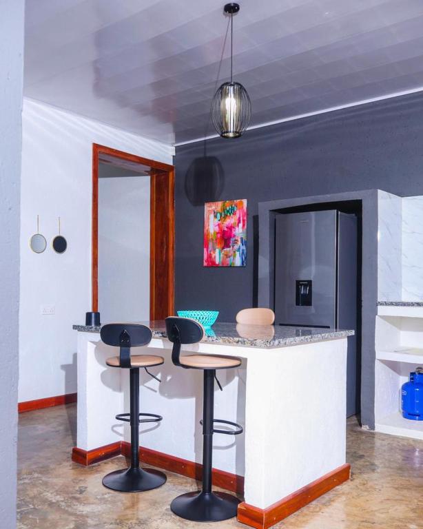 a kitchen with two bar stools and a counter at Torriam Apartments in Chongwe