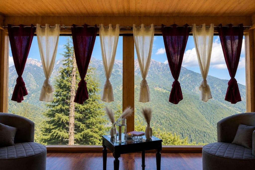 a room with a large window with a mountain view at The Woodnest Tandi in Jibhi