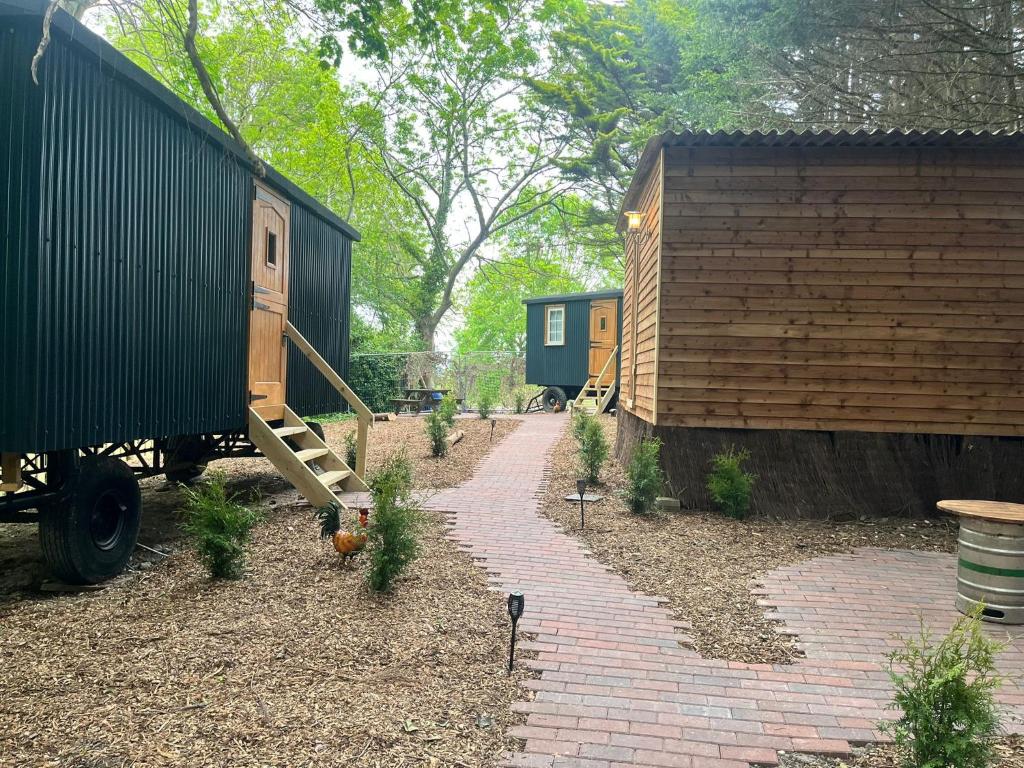 a garden with a house and a brick path at Half Moon Shepherds Huts in Plumpton