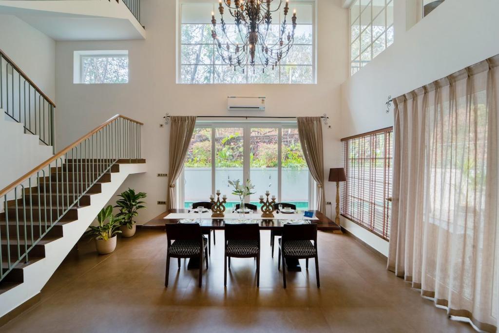 a dining room with a table and chairs and a chandelier at SaffronStays Forest Edge in Siolim