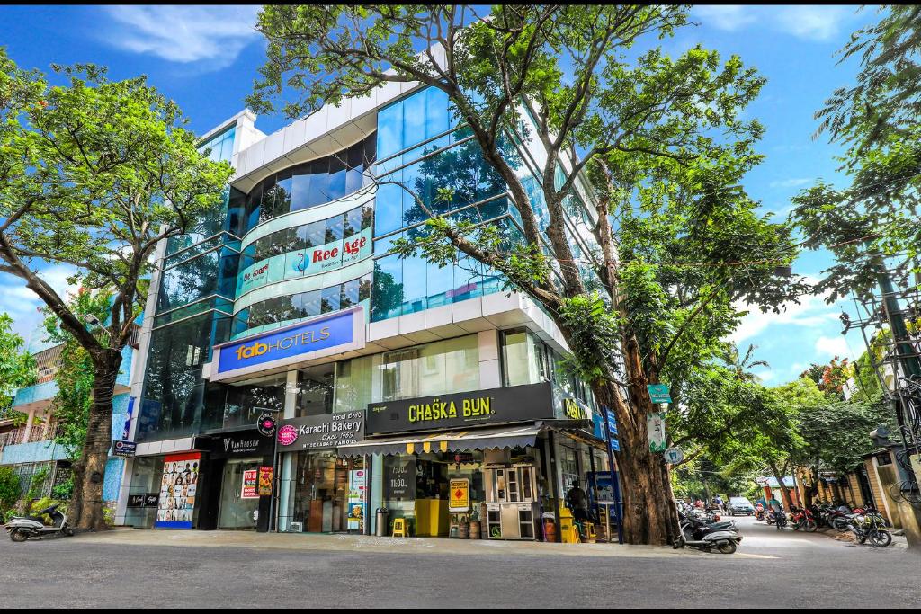 a building on a street with trees in front of it at FabHotel Crown Heights - Nr Koramangala Club in Bangalore
