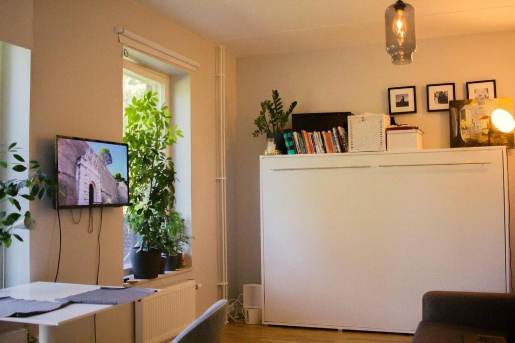 a room with a desk with a window and a door with plants at Green Balcony Studio near Metro in Norsborg