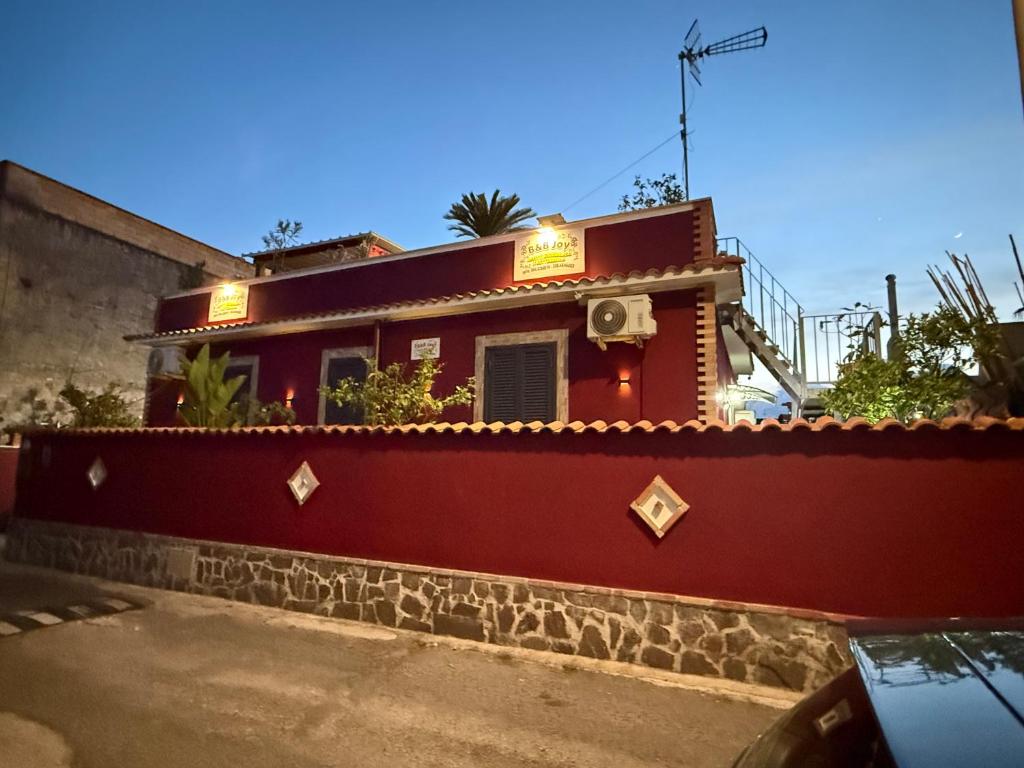 a red building with a sign on the side of it at B&B JOY in Nettuno