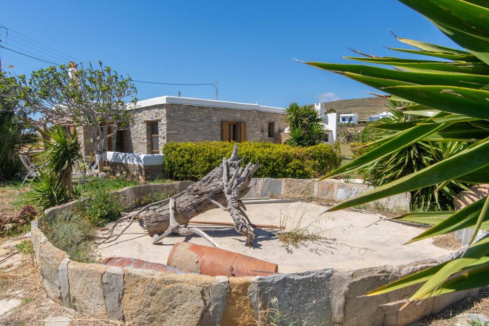 a statue of a tree sitting on top of a stone wall at Liostasi Tinos in Agios Fokas