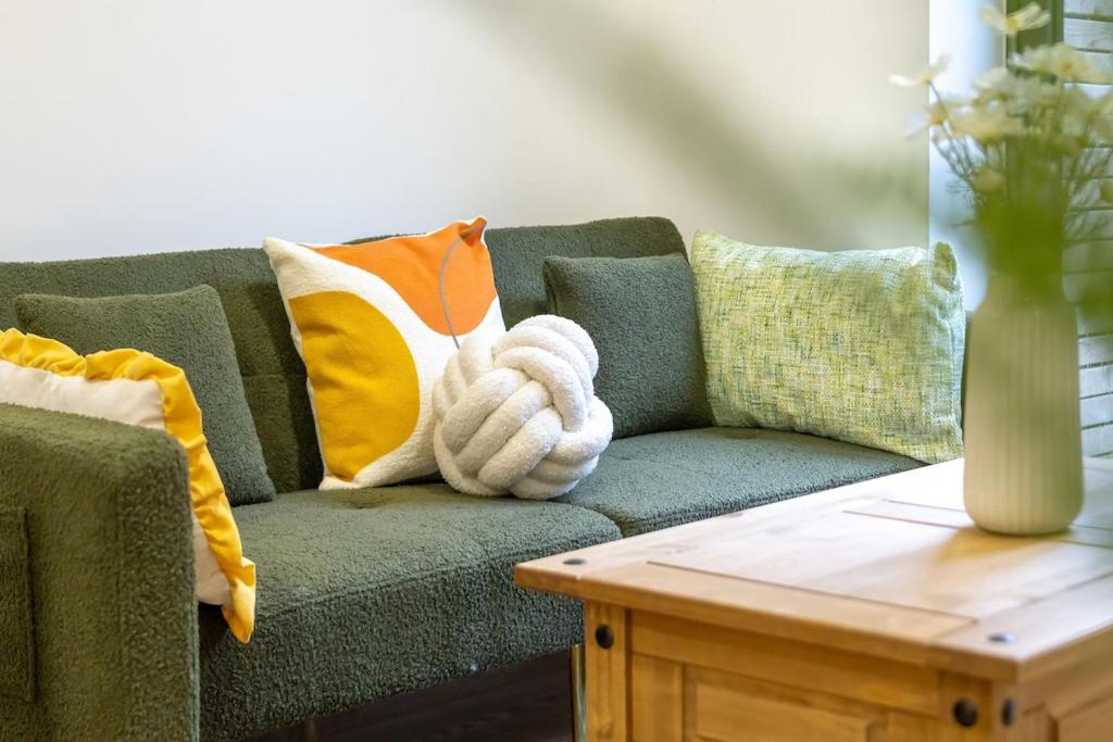 a green couch with pillows and a table at Cozy Urban 2BR with courtyard in Gloucestershire