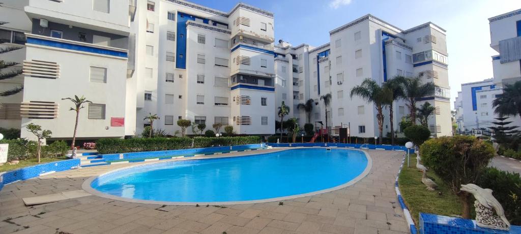 a swimming pool in front of a building at Appartement Résidence fermée avec piscine in Ben Slimane