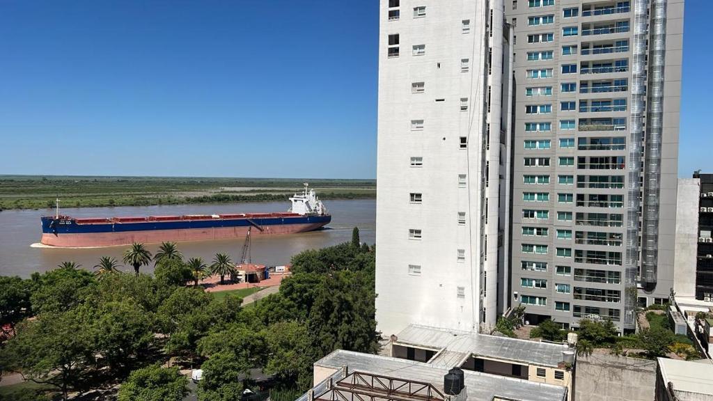 a large container ship in a river between two buildings at Parana in Rosario