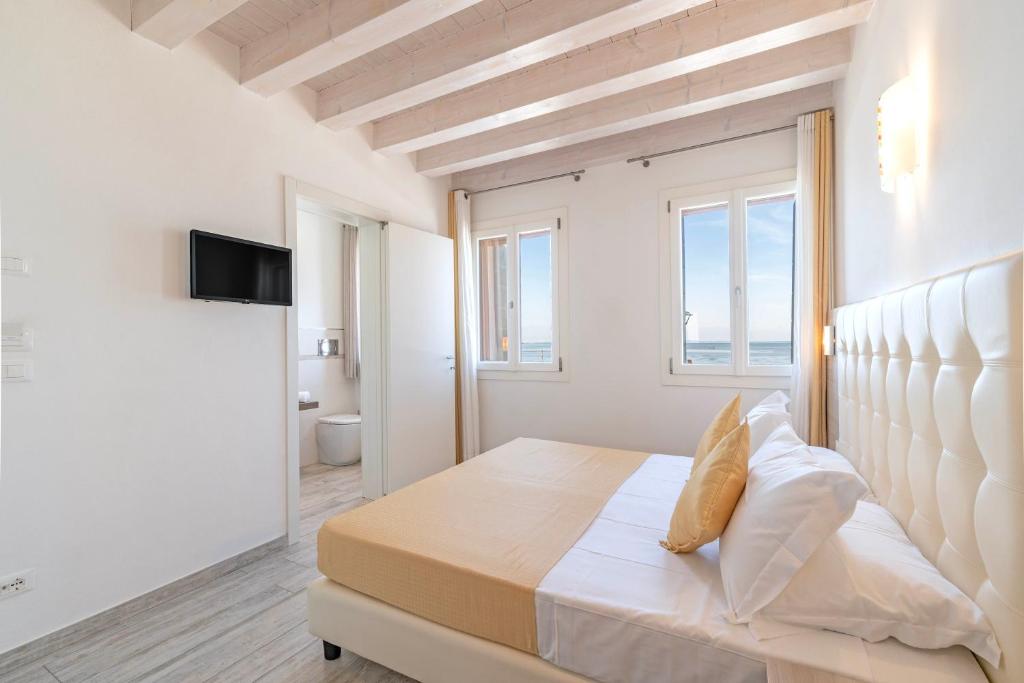 a white bedroom with a large bed and a window at Locanda Stravedo in Pellestrina