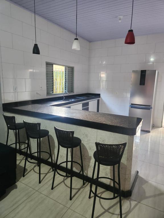 a kitchen with a bar with chairs and a refrigerator at Casa Mirante da Lua in Cavalcante