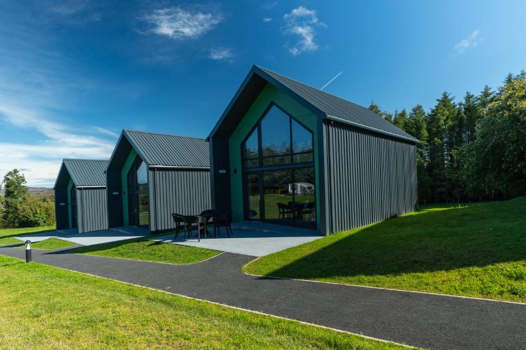 a green building with glass doors on a field at Wild Atlantic Camp in Creeslough