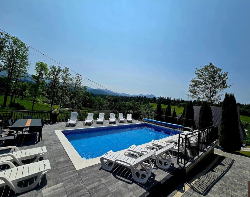 a swimming pool with lounge chairs and a swimming pool at Budzowy Dworek in Murzasichle