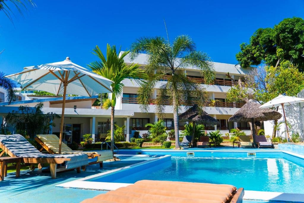 a swimming pool with chaise lounge chairs and a hotel at Villa Bako Hôtel in Nosy Be