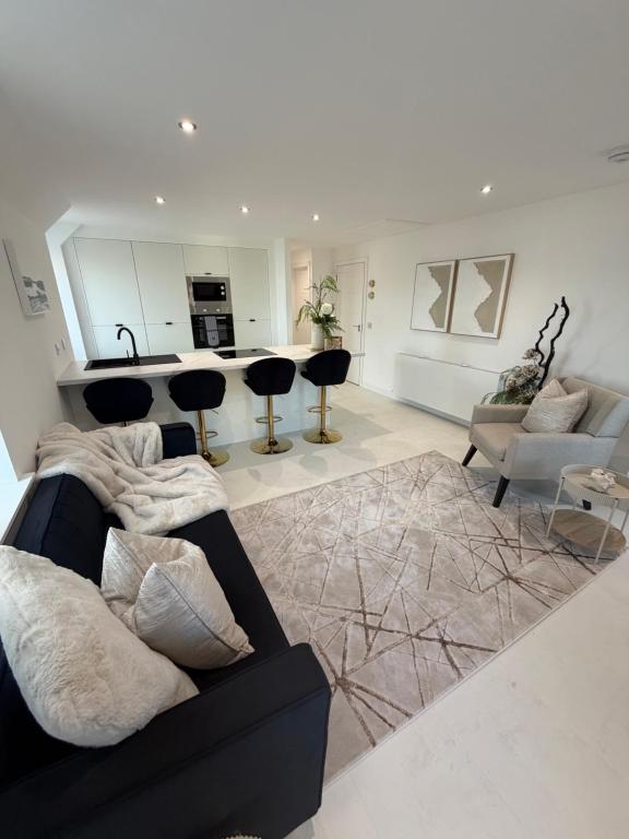 a living room with a black couch and a kitchen at The Esplanade Apartment in Peterhead