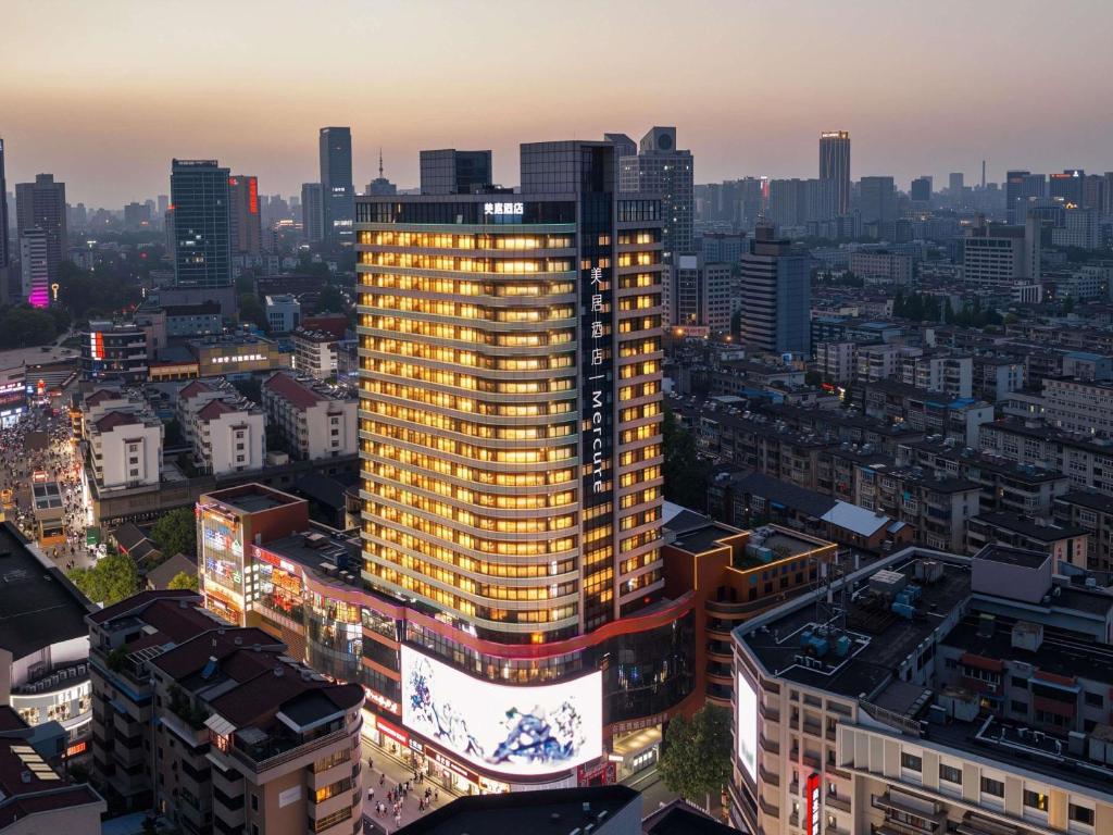 a tall yellow building in a city at night at Mercure Hefei Huaihe Road in Hefei